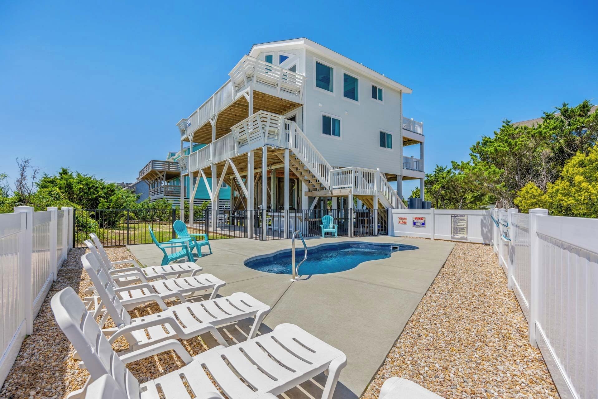 A two-story building with a pool area, outdoor seating, and a staircase leading to the upper floor.