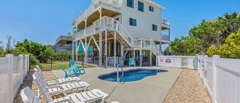 A two-story building with a pool area, outdoor seating, and a staircase leading to the upper floor.