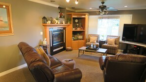 A living room with a fireplace, leather sofas, a television, and a ceiling fan.