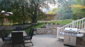 An outdoor patio with a grill, dining table, and chairs.