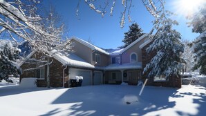 A two-story house with a snow-covered driveway and a garage.