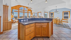 A spacious kitchen with a large island, wooden cabinets, and a view of the ocean. - Semi-Oceanfront Home w/ Hot Tub, Smart TVs, Community Tennis/Pickleball Courts (Rodanthe)