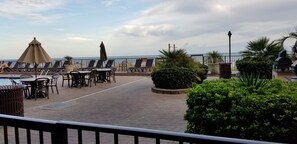 Una terrazza con posti a sedere all'aperto, una piscina e vista mare.