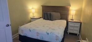 Un letto rifatto con lenzuola a fiori, due comodini con lampade e una testiera in legno.