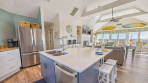 Een moderne keuken met een groot eiland, roestvrijstalen apparatuur en uitzicht op de oceaan.