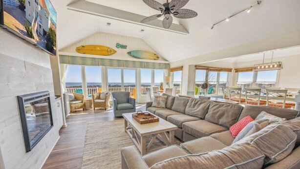 Een ruime woonkamer met een grote modulaire bank, een open haard en uitzicht op zee.