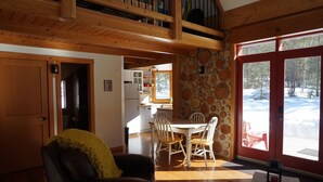 A cozy living room with a fireplace, wooden furniture, and a dining area with a stone wall. - Beautiful eco-building in the heart of the Rocky mountains. All modern amenities (golden)