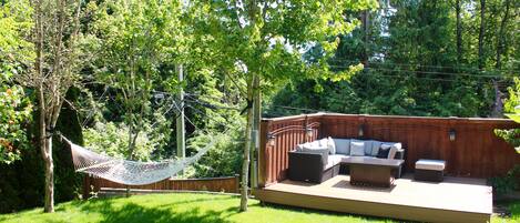 Ein Garten mit Holzterrasse, Gartenmöbeln, einer Hängematte und einem Holzzaun.