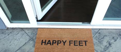 Un felpudo marrón con la inscripción "HAPPY FEET" colocado en la entrada de un edificio.