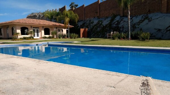 Una piscina con superficie de agua azul cristalina, rodeada por un borde de hormigón.