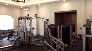 Ein Fitnessraum mit unterschiedlichen Trainingsgeräten, darunter ein Squat-Rack, eine Bankpresse und Kurzhanteln.