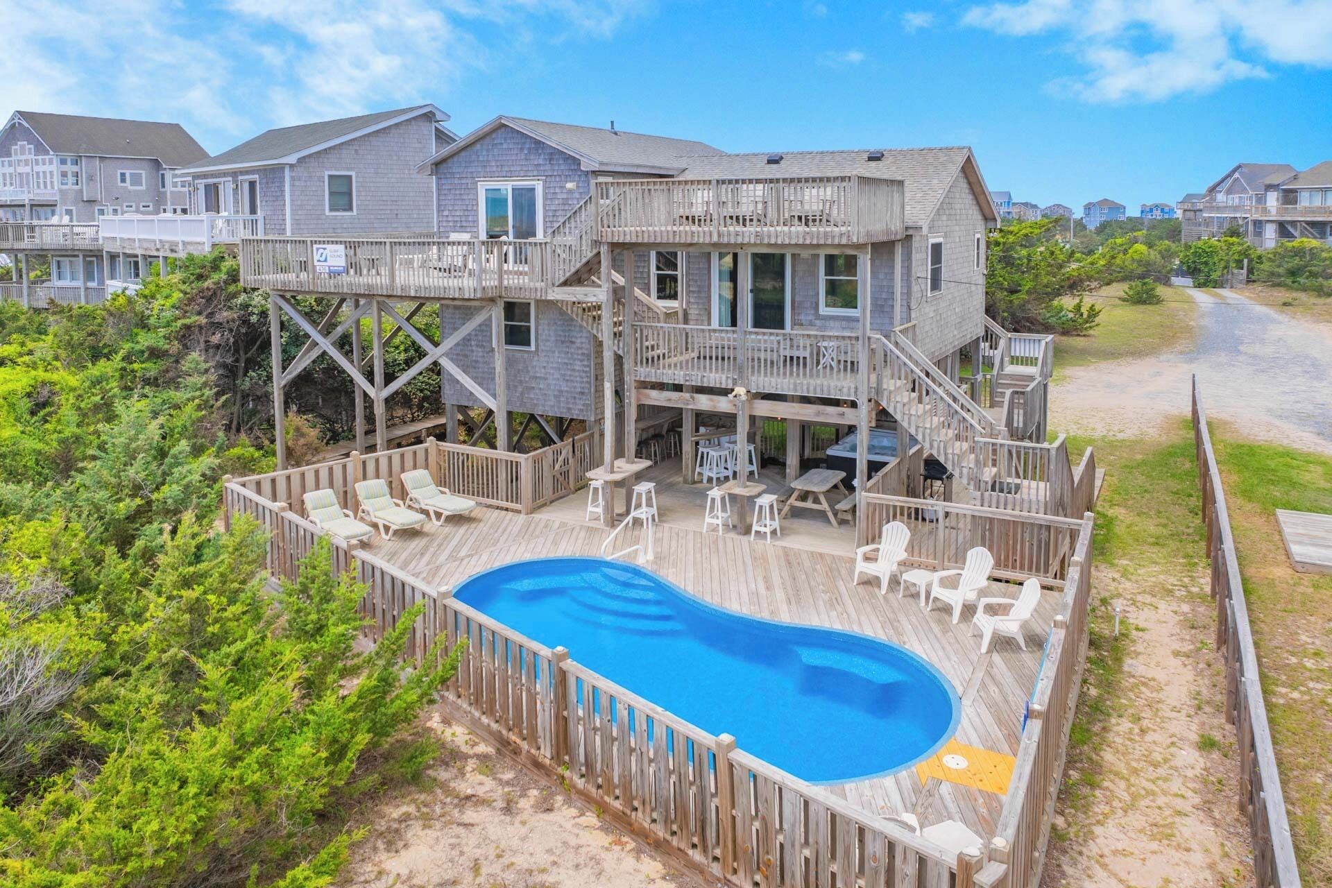 Une maison à deux étages avec une terrasse en bois et une piscine.