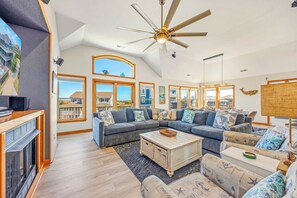 A spacious living room with a large sectional sofa, a coffee table, and a ceiling fan.