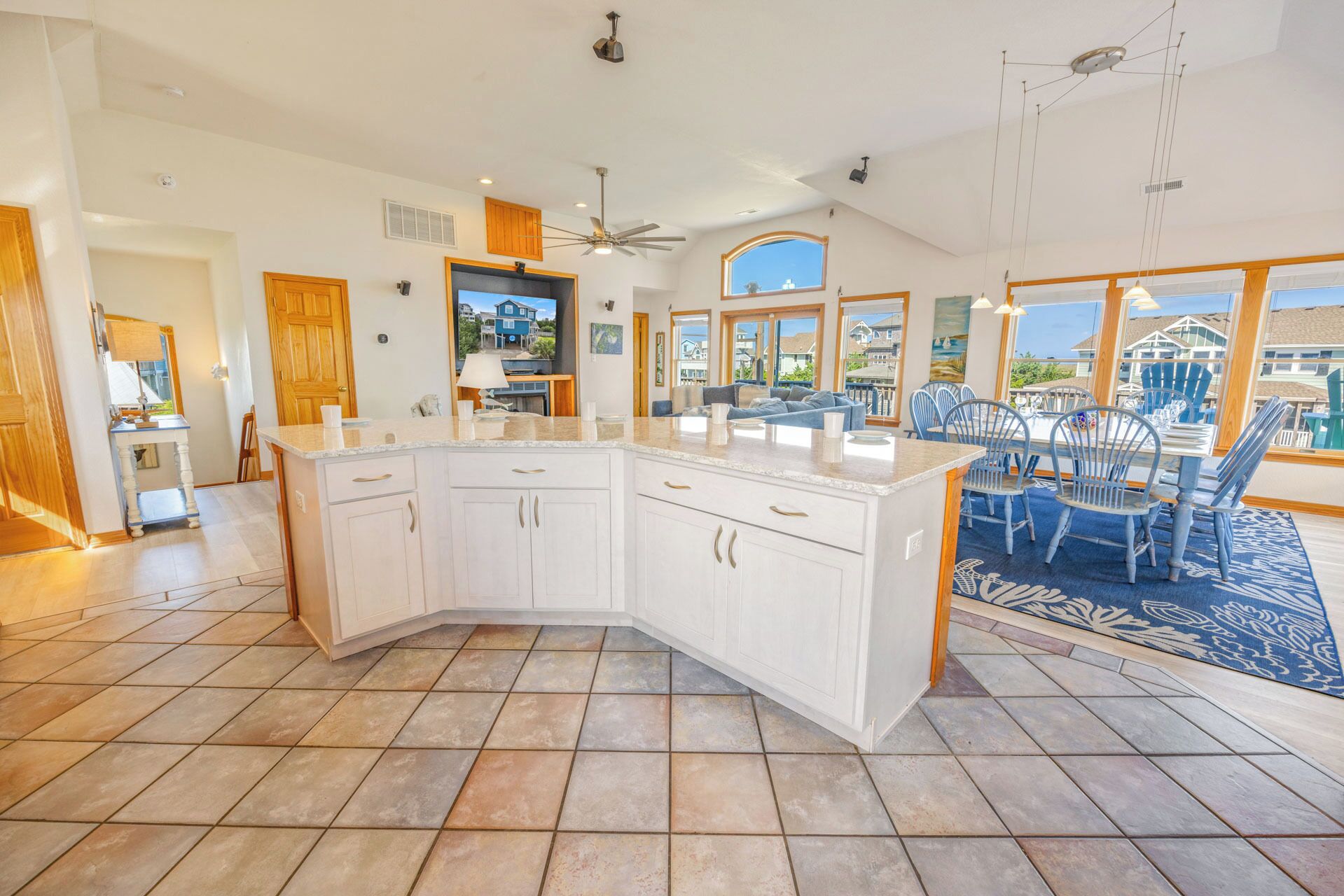 A spacious kitchen with a large island, white cabinetry, and a view of the outside.