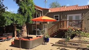 Eine Terrasse mit Gartenmöbeln, ein überdachter Sitzbereich und eine Treppe zu einer Holzterrasse.