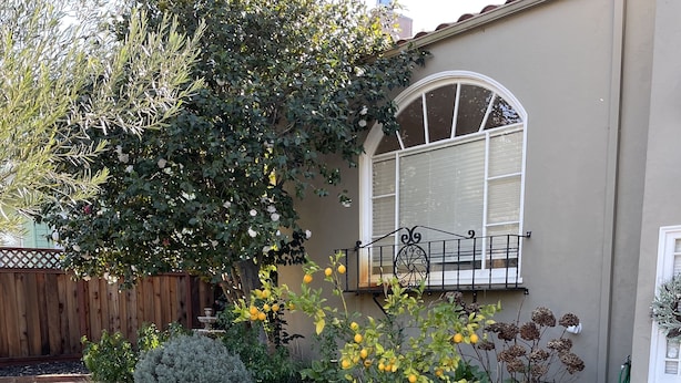 Ein wohnlicher Garten mit einem Kiesweg, der zu einem Haus mit großem Fenster und Balkon führt.