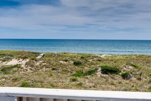 A coastal landscape with a sandy beach and sparse vegetation.