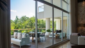 A spacious balcony with a wooden deck, outdoor seating, and large glass doors leading to an interior space. - Grand Luxxe Riviera Maya 3 Bedroom Residence (SPRING BREAK 2020 - 3/14-21) (Riviera Maya)