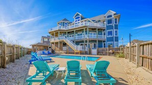 A beachfront property with a large pool, multiple decks, and outdoor seating.