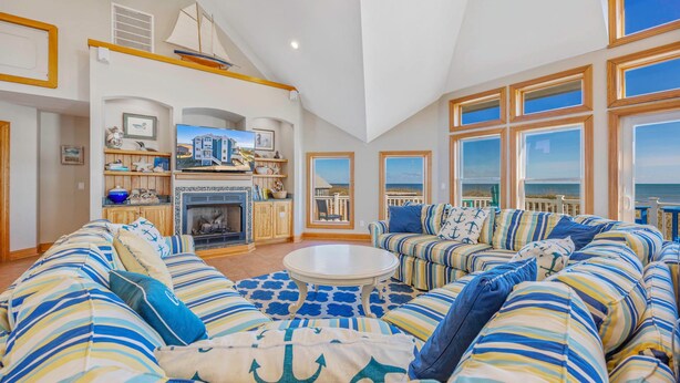 A spacious living room with a fireplace, large windows, and a view of the ocean.