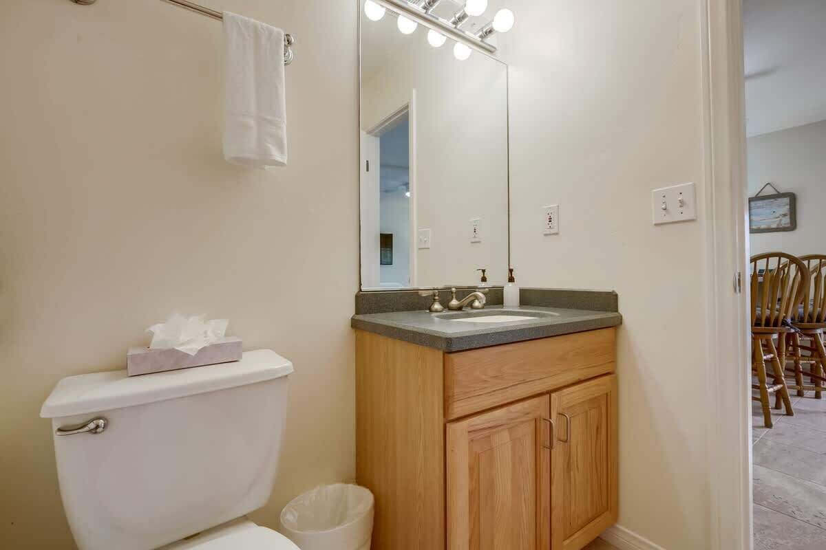 Une salle de bain équipée de toilettes, d’un lavabo, d’un miroir et de meubles en bois.