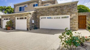A two-story house with stone facade, two attached garages, and a paved driveway. - Driftwood your perfect beach getaway! (La Jolla)