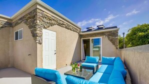 An outdoor patio with a sofa set, a table, and a door. - Driftwood your perfect beach getaway! (La Jolla)