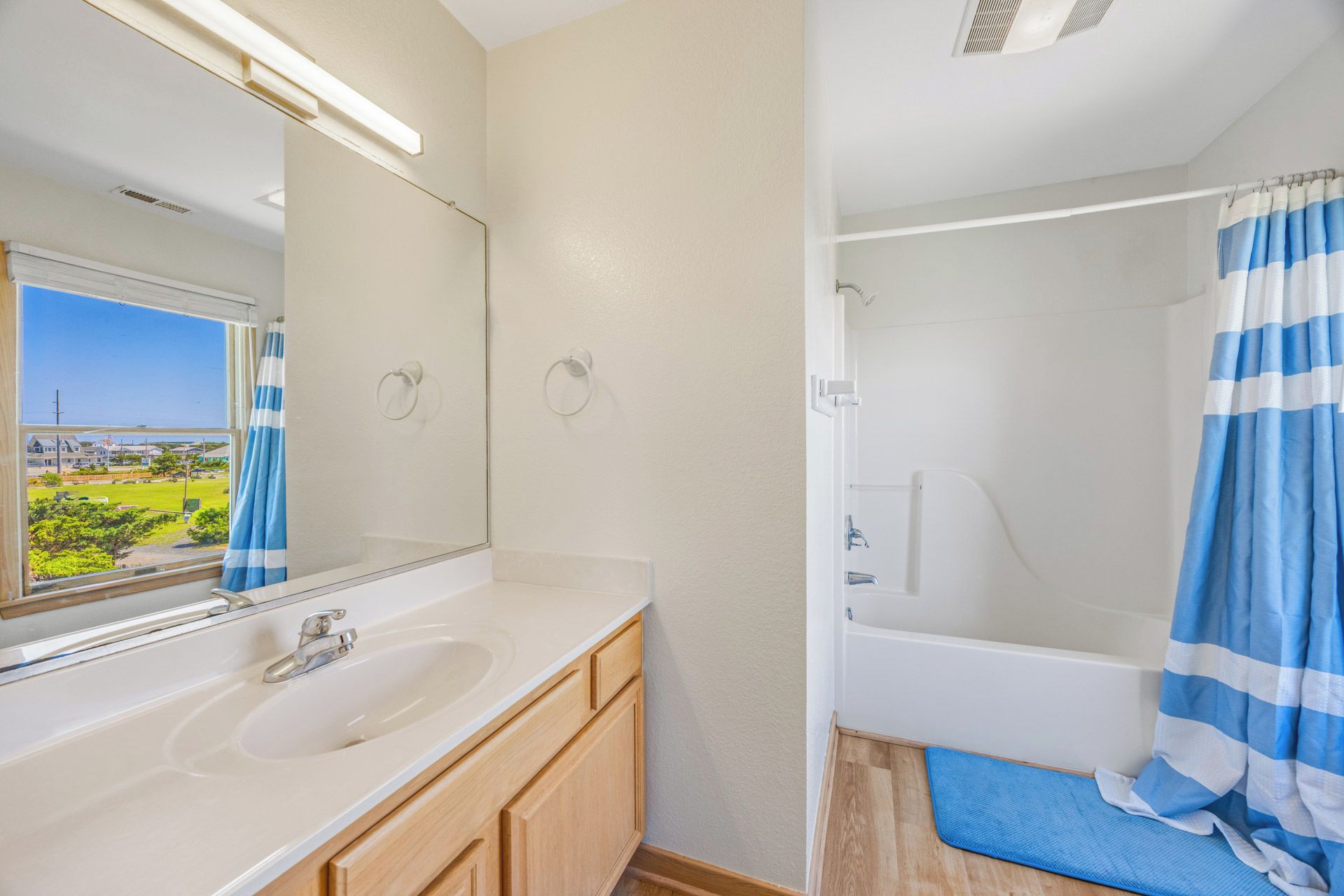A bathroom with a large mirror, two sinks, a bathtub, and a shower curtain.