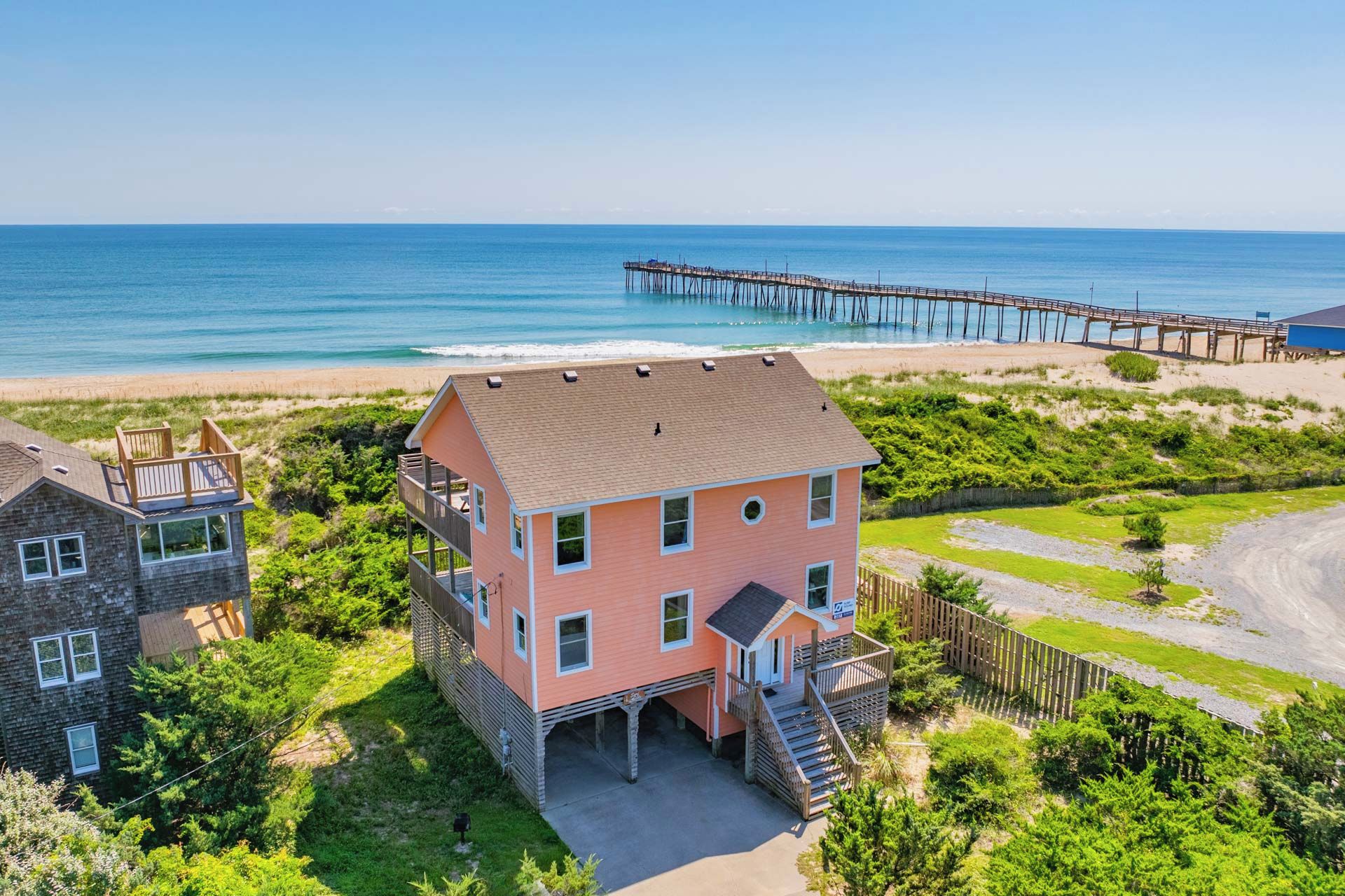 Ein zweistöckiges Haus mit Balkon in Strandnähe und in der Nähe eines Piers.