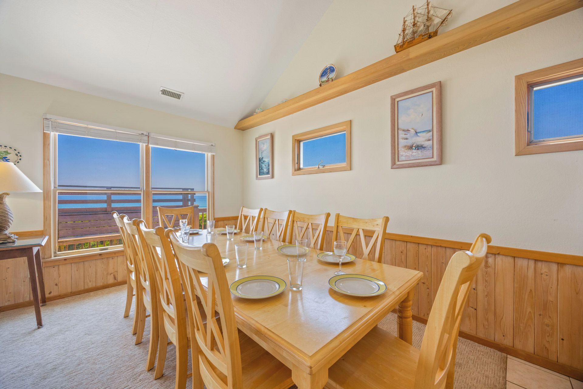 A dining room with a large table, chairs, and a view of the ocean.