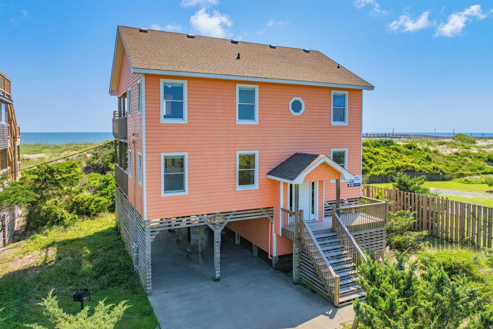 Une maison à deux étages avec un balcon, un petit porche et une clôture en bois.