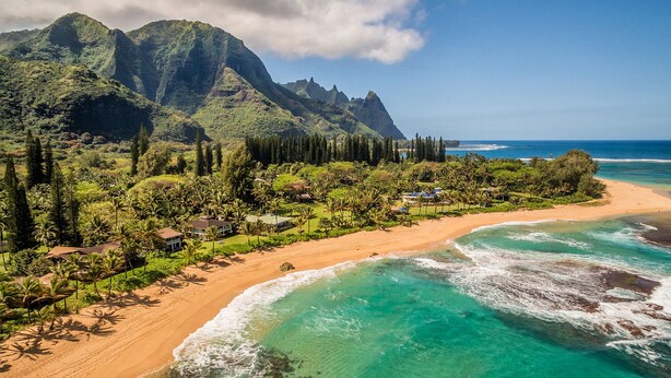 A coastal resort with a sandy beach, clear turquoise waters, and lush greenery.