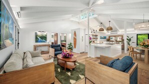 A spacious living area with a high ceiling, a dining area, and a kitchen with a central island.