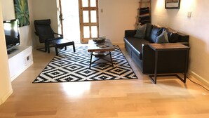 Una sala de estar con sofá, mesa de centro, televisor y alfombra estampada.