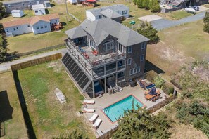 A multi-story building with a large balcony, a swimming pool, and a fenced yard.