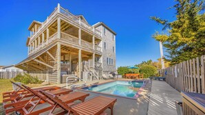 A two-story wooden house with a pool, outdoor seating, and a covered patio area. - Semi-Oceanfront Dog Friendly Home w/ Pool, Hot Tub, Game Room, Fenced Yard (Salvo)