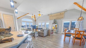 A spacious kitchen with a large island, bar stools, and a dining area with wooden chairs and a table. - Semi-Oceanfront Dog Friendly Home w/ Pool, Hot Tub, Game Room, Fenced Yard (Salvo)
