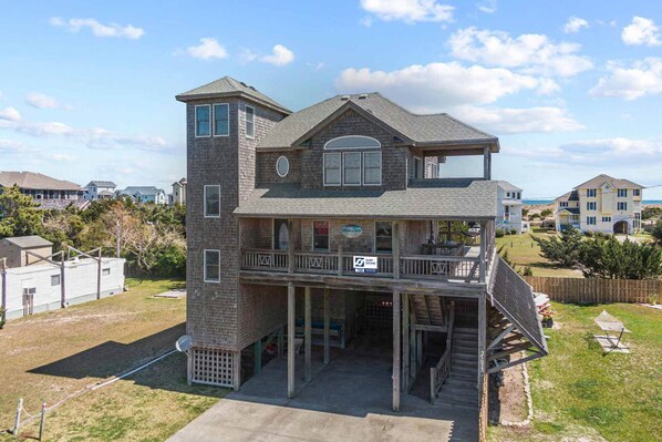 A two-story house with a balcony, a garage, and a visible sign for a surfboard rental.