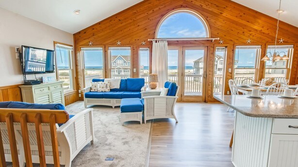 A spacious room with a high ceiling, wooden walls, and large windows offering a view of the beach. - Semi-Oceanfront Home w/ Private Pool, Hot Tub, Basketball. Watch the Waves Crest (Waves)