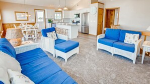 A spacious living area with a sofa set, a dining table with chairs, and a kitchen area with modern appliances. - Semi-Oceanfront Home w/ Private Pool, Hot Tub, Basketball. Watch the Waves Crest (Waves)