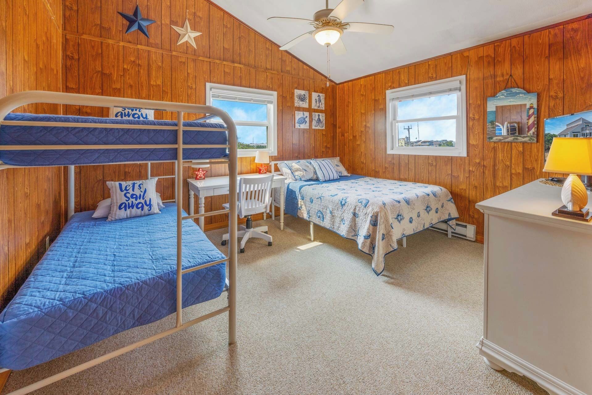 A room with wooden walls, bunk beds, a desk, and a chair.