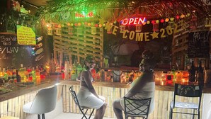 Un bar con mostrador de madera, sillas y decoración festiva con un letrero que dice 'OPEN'.