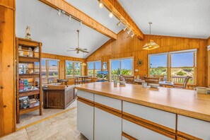A spacious kitchen with a large island, wooden cabinetry, and multiple windows offering views of the outdoors. - Oceanfront Home with Direct Beach Access, Community Pool and Tennis/Pickleball (Avon)