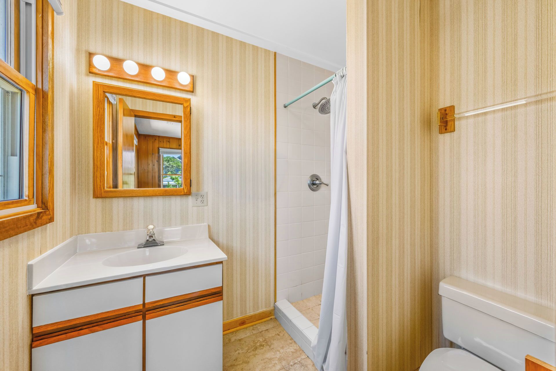 A bathroom with a vanity, mirror, shower, and toilet.