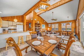 A wooden interior with a dining table set for six, kitchen area, and a ceiling fan. - Oceanfront Home with Direct Beach Access, Community Pool and Tennis/Pickleball (Avon)