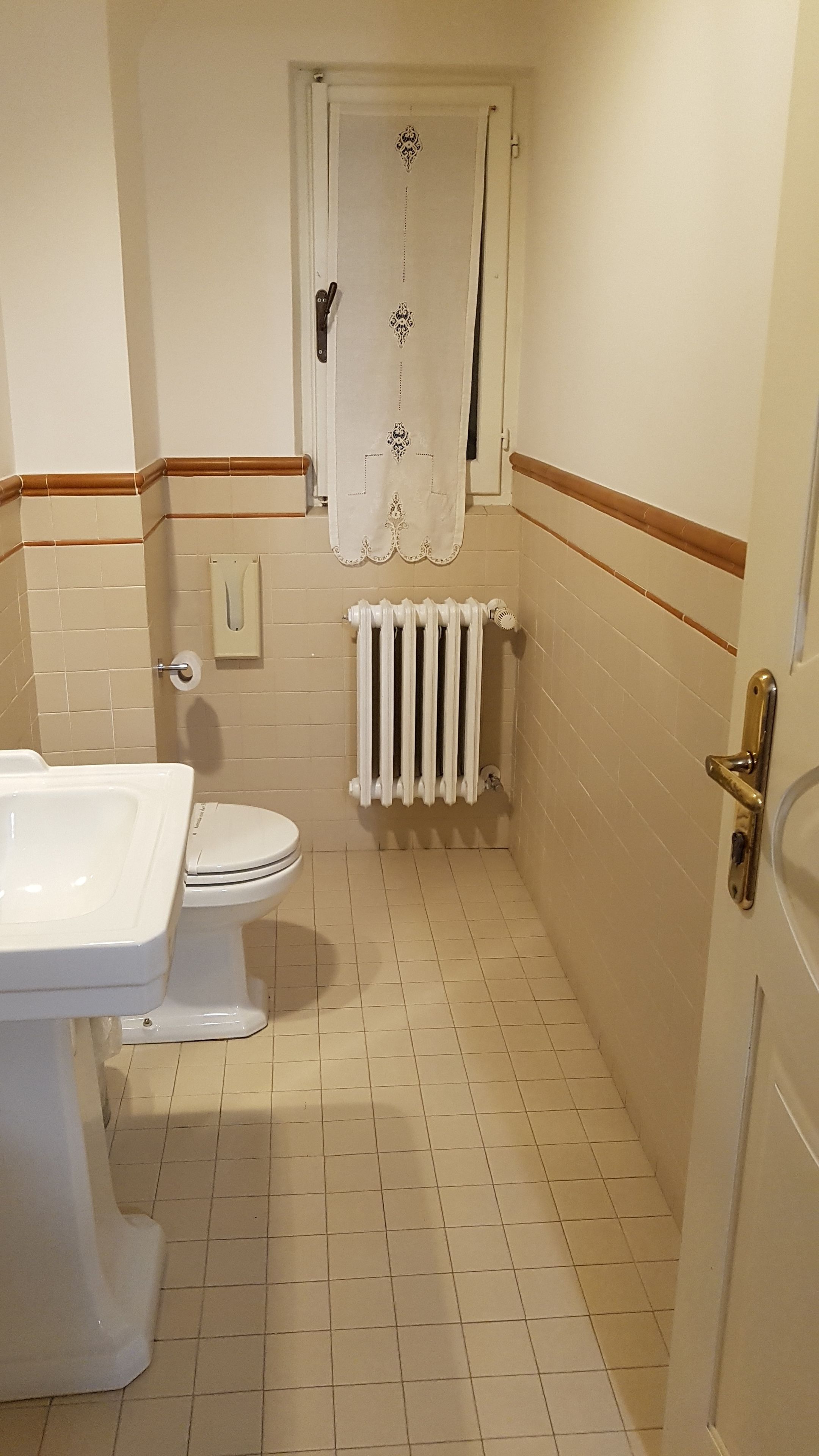 A small bathroom with a toilet, a radiator, and a sink.