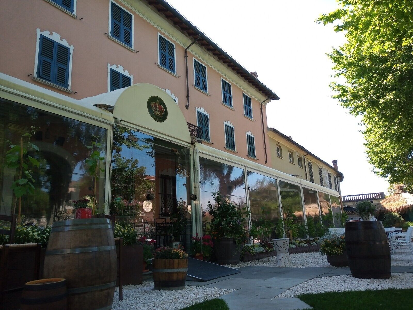 A building with a covered entrance, large windows, and outdoor seating with potted plants.