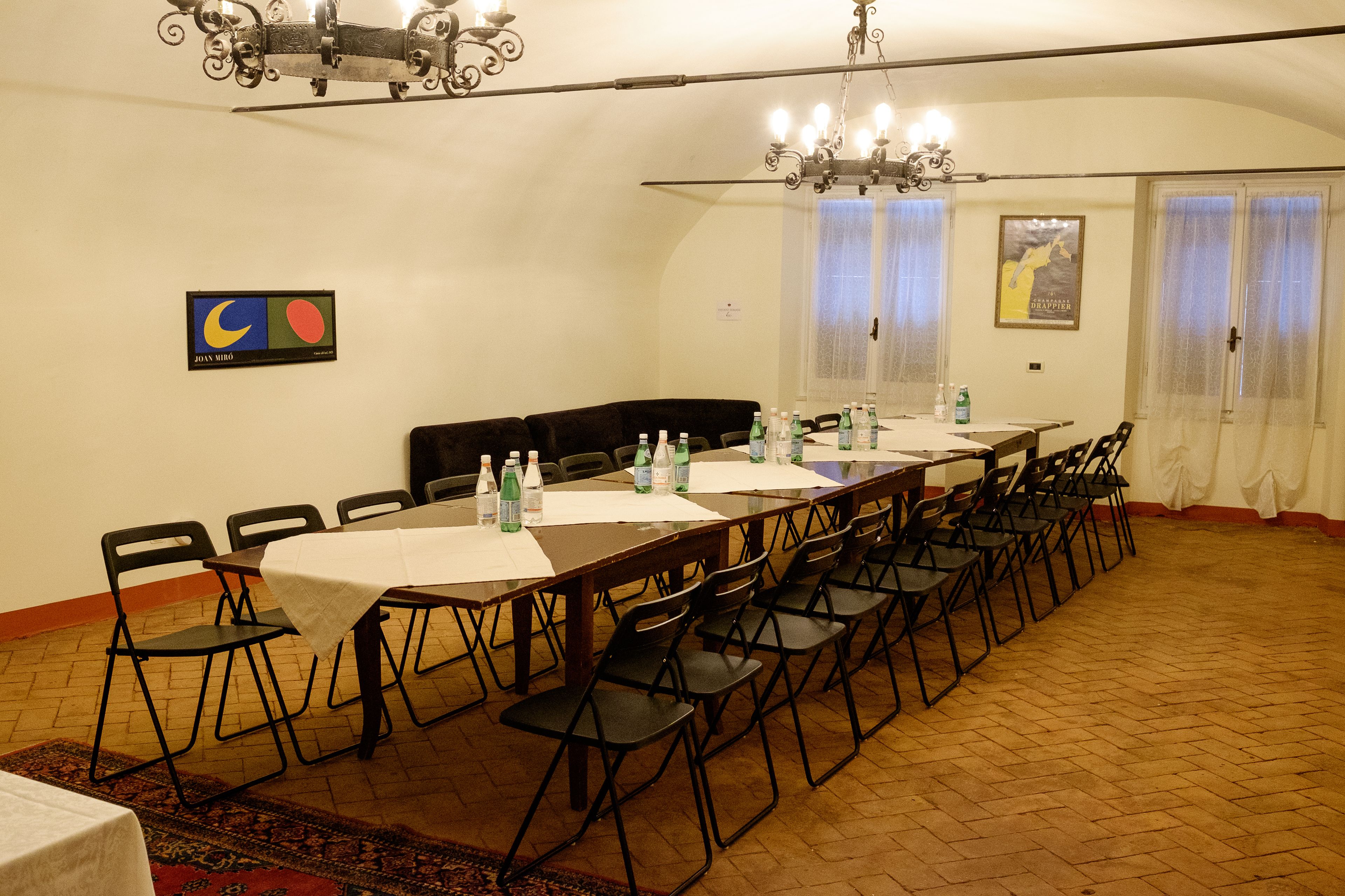 Un salón de conferencias con una mesa larga, sillas y una araña.