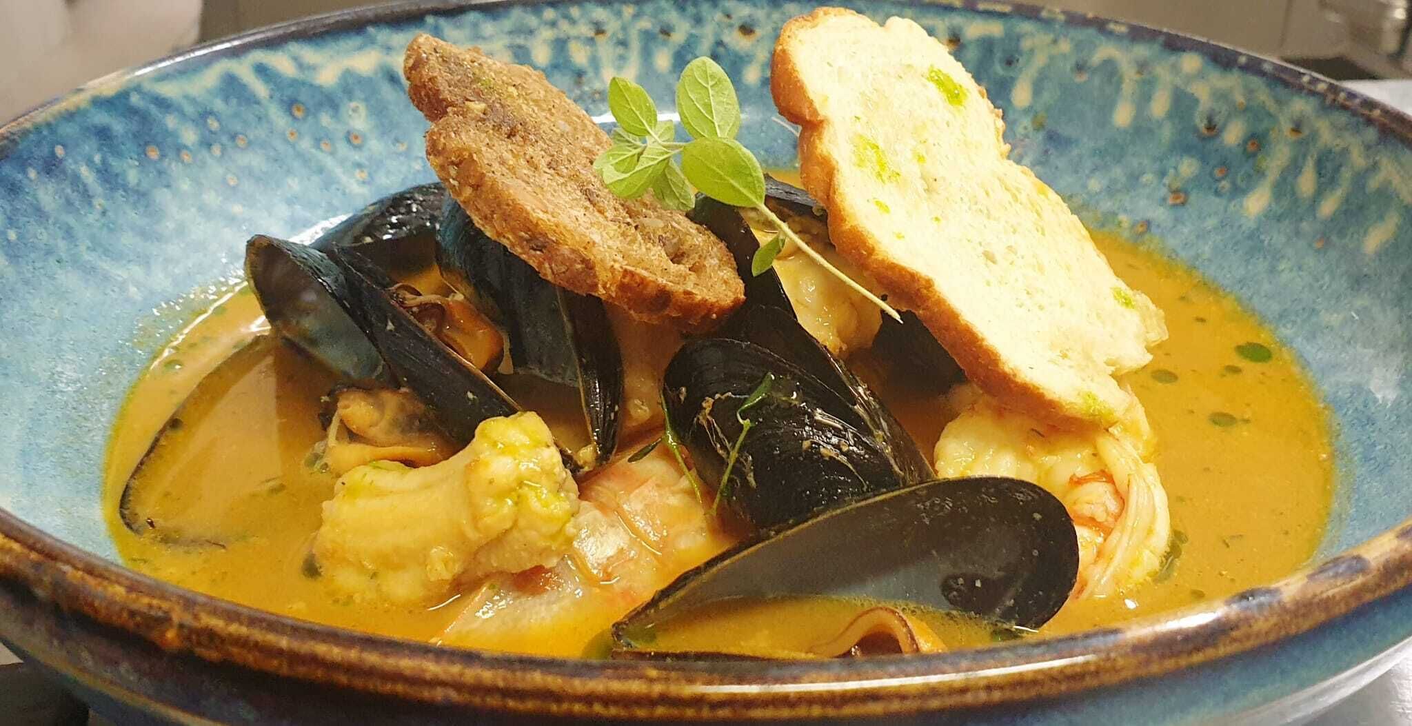 Prato de frutos do mar com mexilhões, camarões e pão em um prato azul.