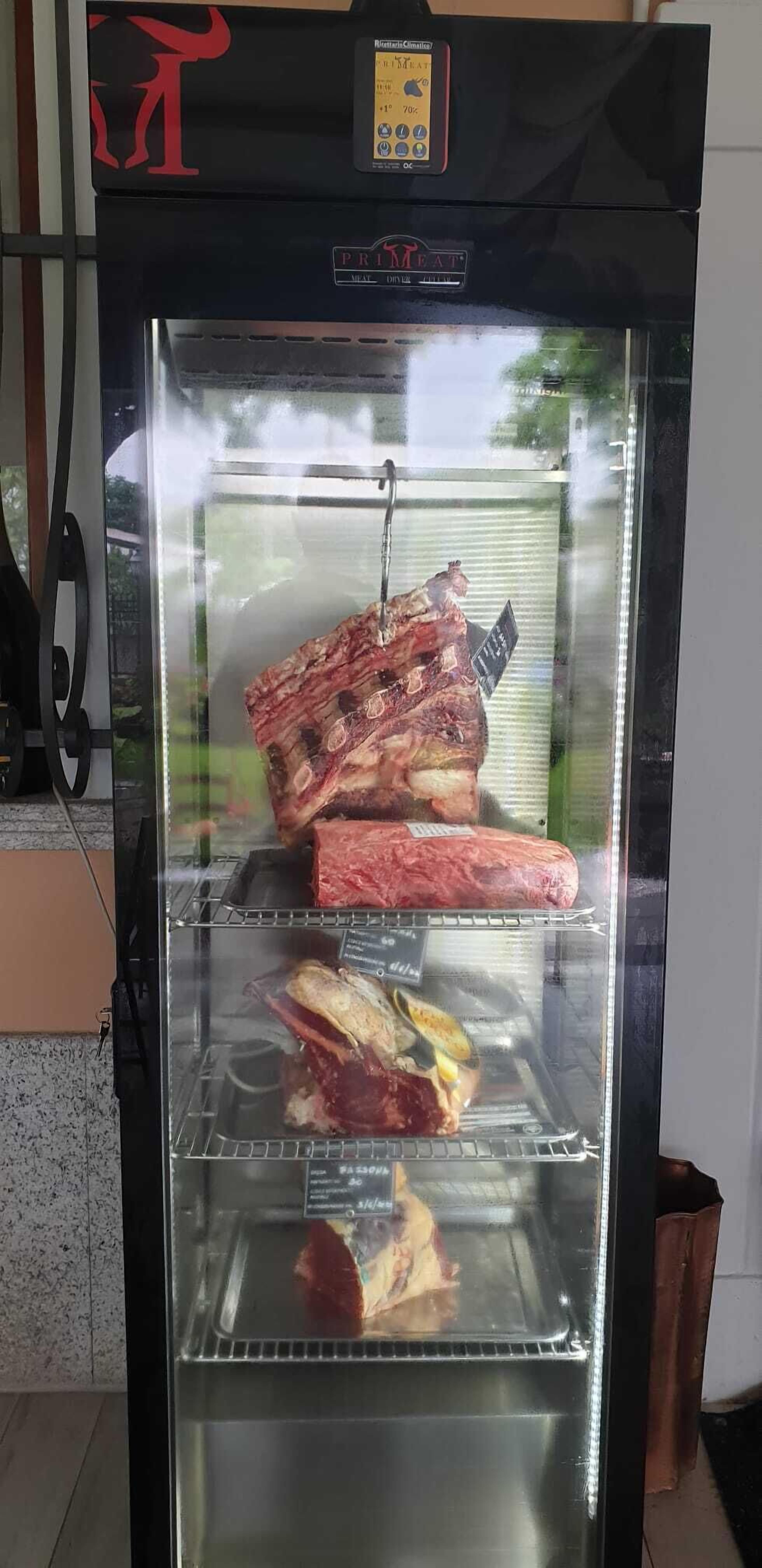 A meat display case with various cuts of meat, including ribs and steaks, in a commercial setting.
